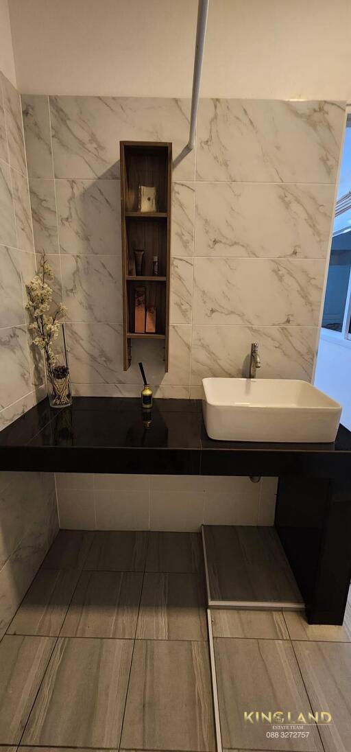 Modern bathroom sink area with marble tiles and shelving