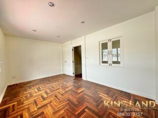 Spacious bedroom with wooden flooring and white walls