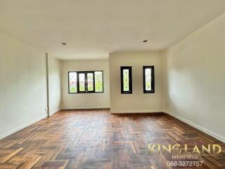 Spacious living area with parquet flooring and multiple windows