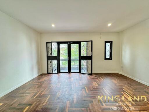 Spacious living room with herringbone wooden flooring and large windows