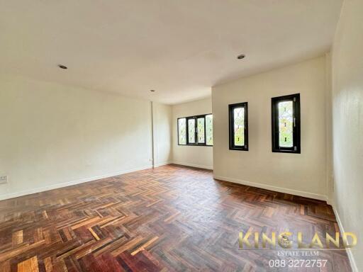 Spacious living room with wooden parquet flooring and multiple windows