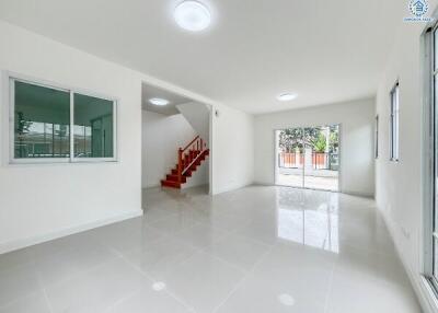 Spacious and bright living room with tiled flooring and stairway to the upper floor.