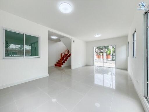 Spacious and bright living room with tiled flooring and stairway to the upper floor.