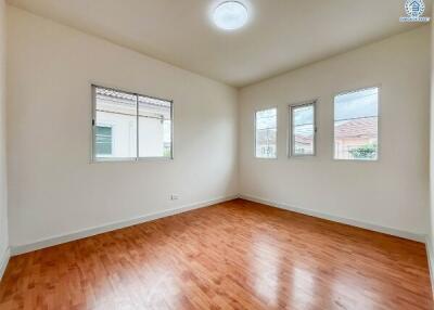 Bright bedroom with hardwood flooring and multiple windows