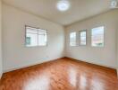 Bright bedroom with hardwood flooring and multiple windows