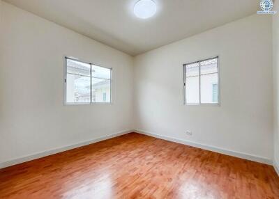 Empty bedroom with wooden floor and two windows