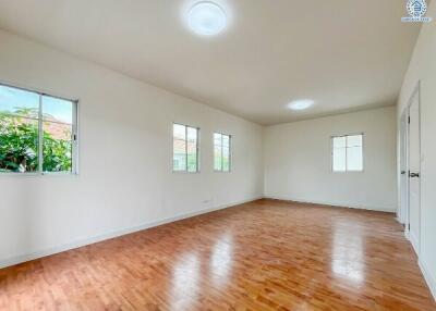 Spacious, well-lit empty room with hardwood floors and multiple windows