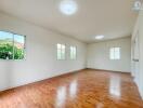 Spacious, well-lit empty room with hardwood floors and multiple windows