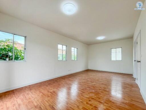 Spacious, well-lit empty room with hardwood floors and multiple windows