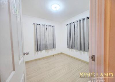 Bright, empty bedroom with wooden floors and grey curtains