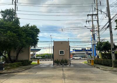 Photo of the entrance to a residential complex with surrounding greenery and power lines.