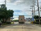 Photo of the entrance to a residential complex with surrounding greenery and power lines.