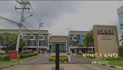 Entrance of Casa City residential complex with visible townhouses and green landscaping