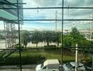 View from the window showing a parking lot, road, and palm trees with a cloudy sky.