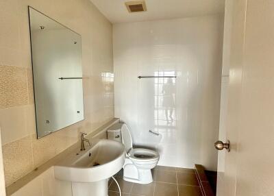 A modern bathroom with a sink, toilet, mirror, and tiled walls.