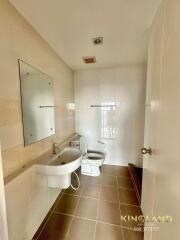 A modern bathroom with a sink, toilet, mirror, and tiled walls.