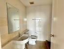 A modern bathroom with a sink, toilet, mirror, and tiled walls.