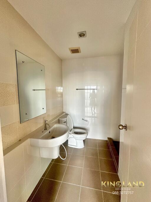 A modern bathroom with a sink, toilet, mirror, and tiled walls.