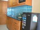 Compact kitchen with wooden cabinets and black countertop