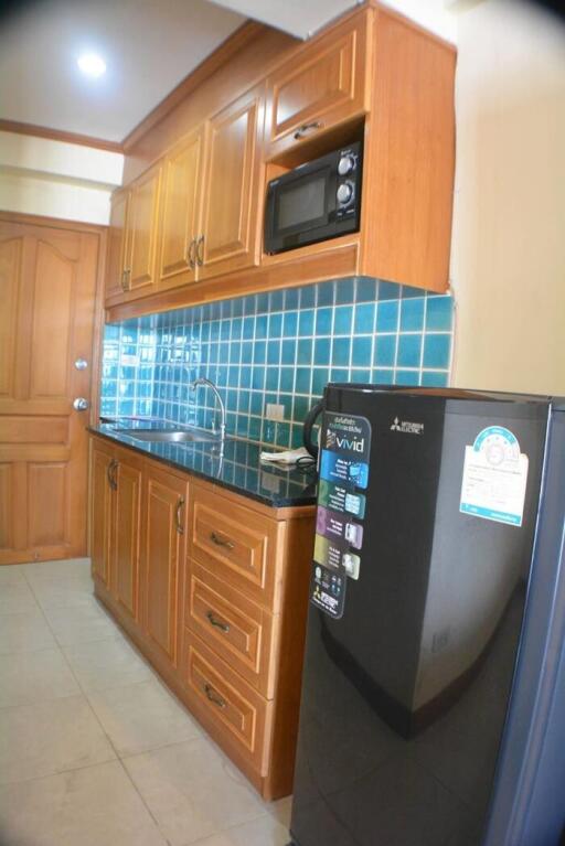 Compact kitchen with wooden cabinets and black countertop