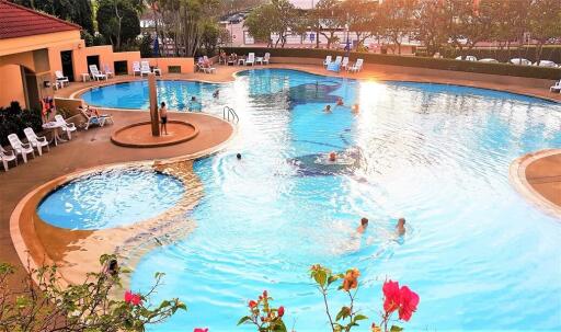 Outdoor swimming pool with people enjoying the water and lounging