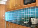 Compact kitchen with wooden cabinets and blue tiled backsplash