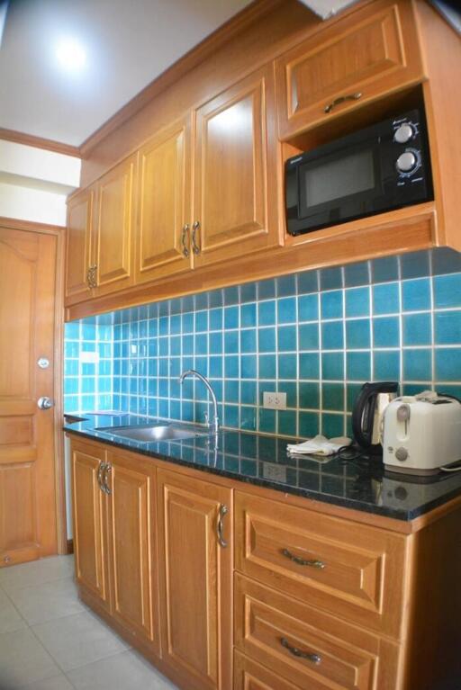 Compact kitchen with wooden cabinets and blue tiled backsplash