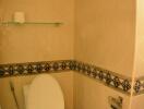 Small bathroom with toilet, decorative tile trim, and wall-mounted toilet roll holder