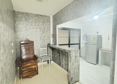 Small kitchen with marble counter, wooden chair, and refrigerator