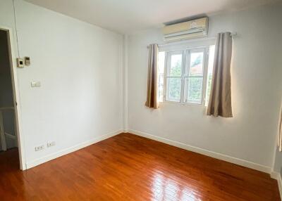 Empty bedroom with hardwood flooring and a window