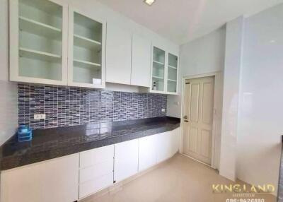 Modern kitchen with white cabinets, black countertop, and mosaic tile backsplash