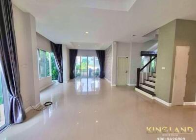 Spacious living room with large windows and staircase