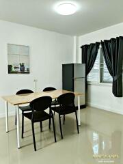 Modern dining area with table, chairs, and refrigerator