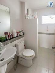 A well-lit bathroom with essential amenities including a sink, toilet, mirror, and storage shelf.