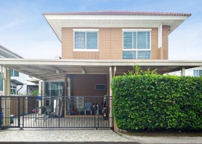 Front view of a two-story house with a covered driveway and greenery