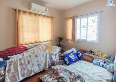 A cozy bedroom with an air conditioner and two beds with stuffed toys