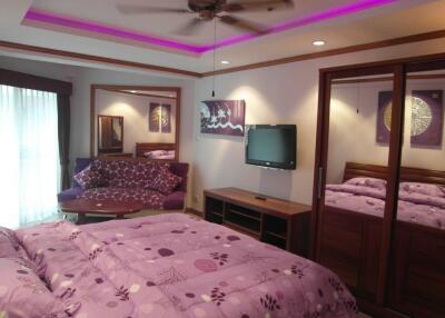 Modern bedroom with purple decor, mirrored wardrobe, and TV