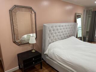 Bedroom with a bed, nightstand, lamp, mirror, and balcony