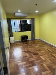 Bright empty bedroom with wooden floors, a window, an air conditioner, and a small table