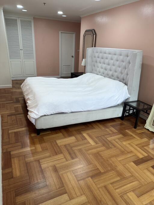 A cozy bedroom with a large bed and parquet flooring