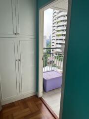 Doorway leading to a small balcony with a purple storage box and cityscape view