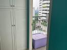 Doorway leading to a small balcony with a purple storage box and cityscape view