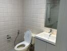 Modern bathroom with tiled walls, a toilet, and a sink.