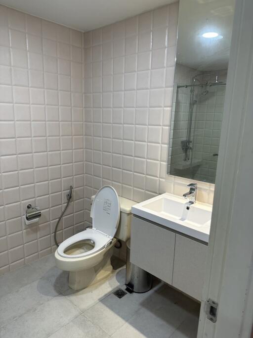 Modern bathroom with tiled walls, a toilet, and a sink.