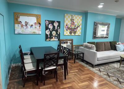 Living and dining area with teal walls, dining table, and couch