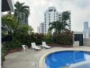 Outdoor pool area with lounge chairs and surrounding greenery