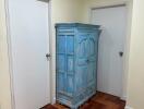 Hallway with wooden parquet flooring and a blue armoire