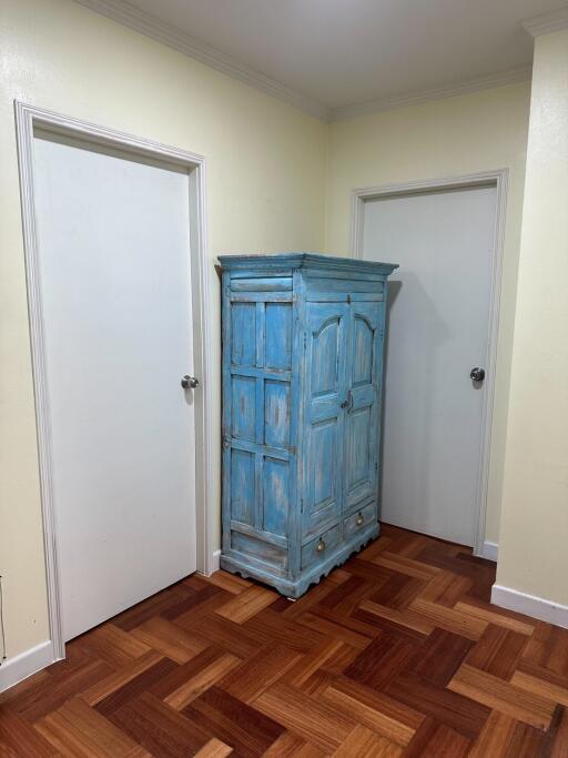 Hallway with wooden parquet flooring and a blue armoire