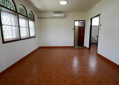 Interior view of a spacious living area with large windows, tiled floor, and air conditioning unit