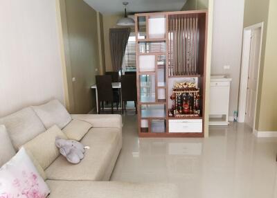 Living room with beige sofa, decorative item, and view into dining area